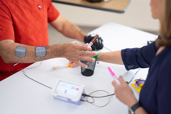 A patient with electrodes on his arm performing hand exercises