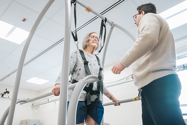 A patient standing while supported by specialized equipment