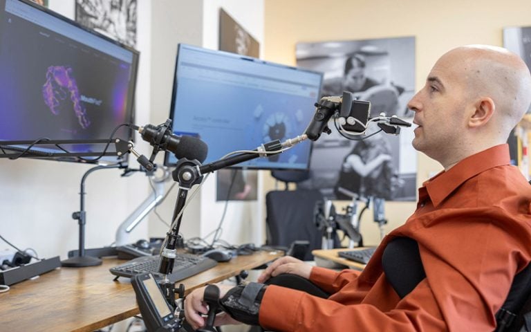 A patient in a wheelchair with a voice control device using a computer